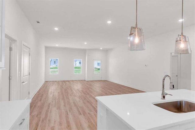 614 Glendale Rd, Scottdale, GA 30079 - kitchen with a sink, light countertops, light wood finished floors, white cabinets, and decorative light fixtures