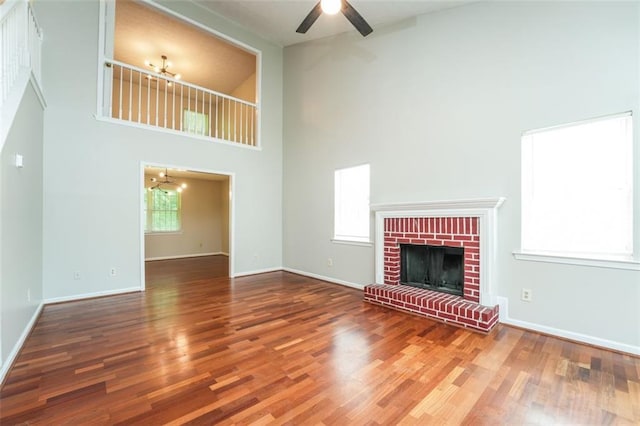 4400 Old Allgood Cir, Stone Mountain, GA 30083 - unfurnished living room featuring a towering ceiling, wood finished floors, ceiling fan, baseboards, and a brick fireplace