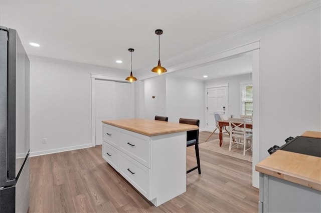 597 Rich Davis Rd, Hiram, GA 30141 - kitchen with wooden counters, a breakfast bar area, white cabinetry, light wood-style floors, and ornamental molding