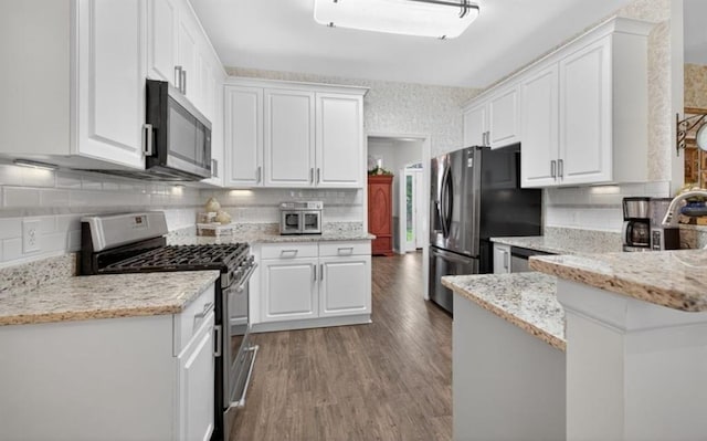 49 Inverness Ct, Hiram, GA 30141 - kitchen featuring appliances with stainless steel finishes, white cabinetry, tasteful backsplash, wood finished floors, and light stone countertops