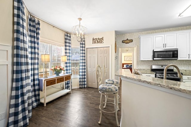 49 Inverness Ct, Hiram, GA 30141 - kitchen with appliances with stainless steel finishes, a chandelier, dark wood-type flooring, white cabinets, and light stone countertops