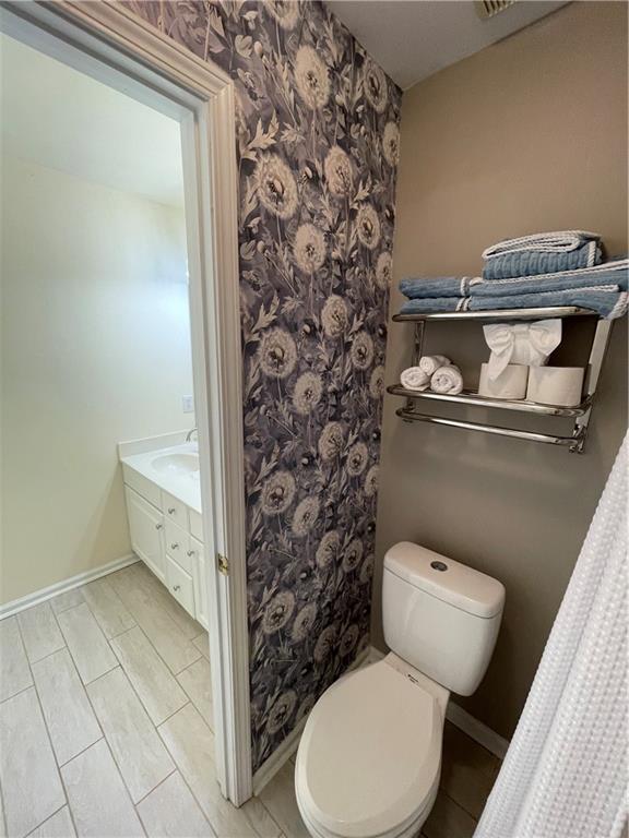 49 Inverness Ct, Hiram, GA 30141 - bathroom featuring toilet, wallpapered walls, baseboards, and vanity