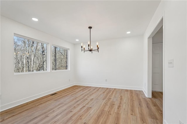 spare room featuring light hardwood / wood-style floors and a notable chandelier