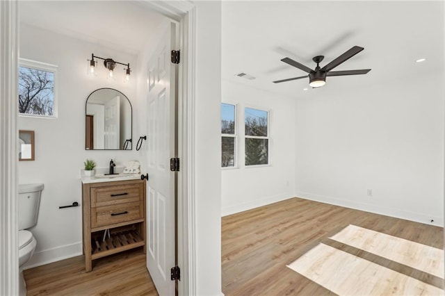 bathroom featuring vanity, hardwood / wood-style floors, toilet, and ceiling fan