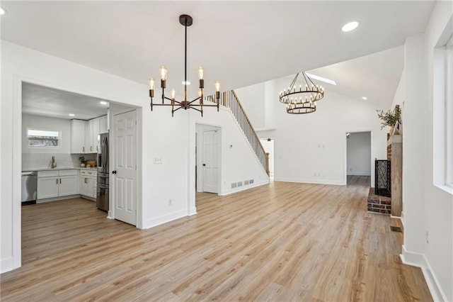 kitchen featuring appliances with stainless steel finishes, decorative light fixtures, white cabinetry, a chandelier, and light hardwood / wood-style floors