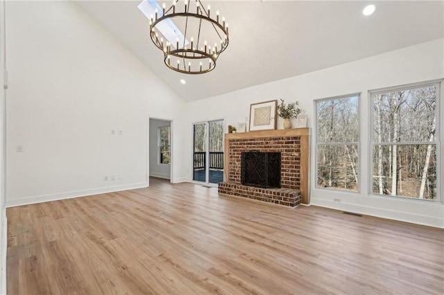 unfurnished living room featuring wood-type flooring, a fireplace, a chandelier, and high vaulted ceiling