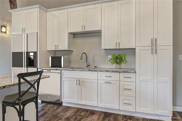 kitchen with light stone counters, high quality fridge, sink, white cabinetry, and stainless steel dishwasher