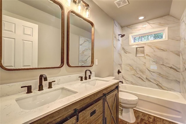 full bathroom with tiled shower / bath, toilet, vanity, and wood-type flooring