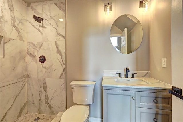 bathroom featuring toilet, vanity, and tiled shower