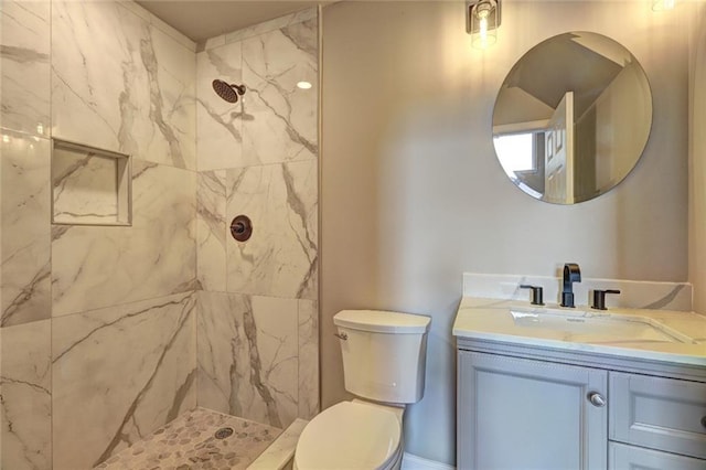 bathroom featuring toilet, vanity, and tiled shower