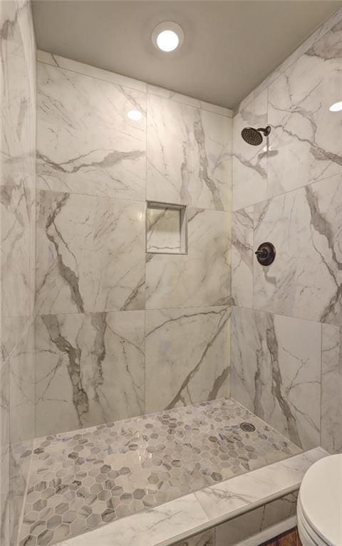 bathroom featuring a tile shower and toilet