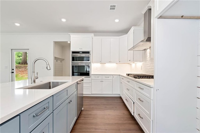 200 College Ave, Commerce, GA 30529 - kitchen with a sink, appliances with stainless steel finishes, wall chimney exhaust hood, light countertops, and white cabinetry