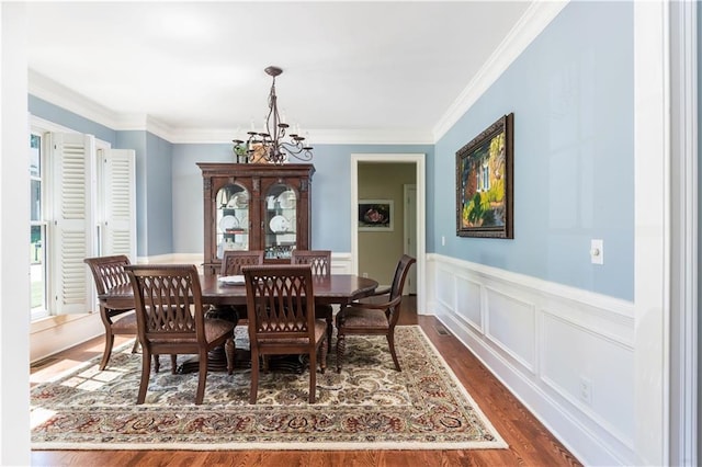 dining area with a chandelier, crown molding, and dark wood-type flooring