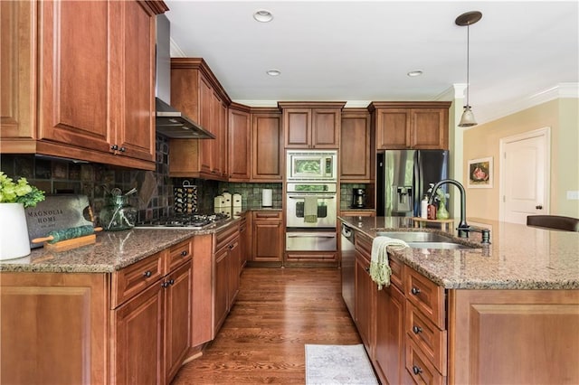 kitchen featuring appliances with stainless steel finishes, sink, pendant lighting, dark hardwood / wood-style floors, and an island with sink