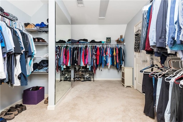 walk in closet with carpet floors and vaulted ceiling