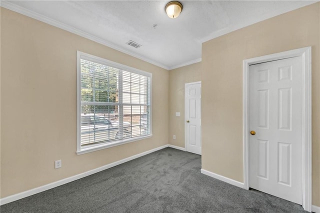 unfurnished room with visible vents, dark carpet, baseboards, and ornamental molding