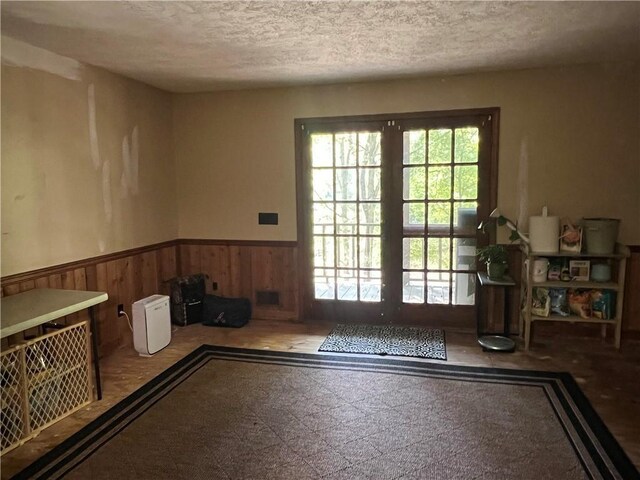 6245 Bannister Rd, Cumming, GA 30028 - doorway featuring a textured ceiling, wood walls, and wainscoting