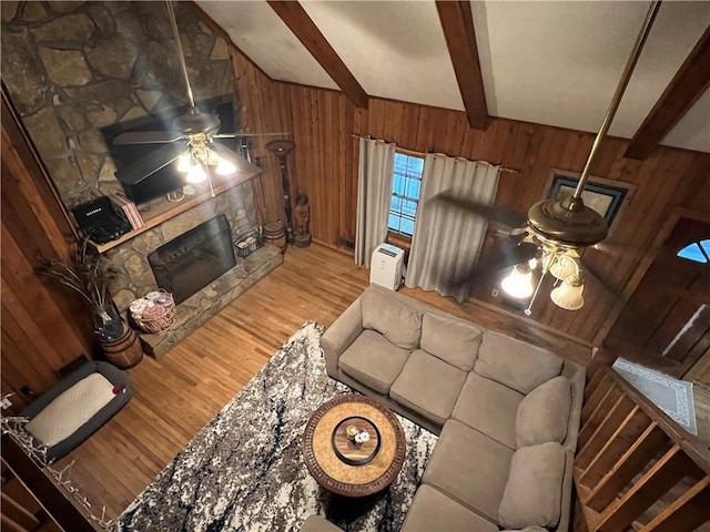6245 Bannister Rd, Cumming, GA 30028 - living room featuring ceiling fan, a stone fireplace, wooden walls, wood finished floors, and beamed ceiling