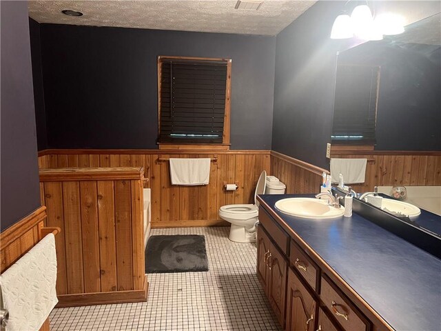 6245 Bannister Rd, Cumming, GA 30028 - bathroom with a wainscoted wall, toilet, wood walls, a textured ceiling, and vanity