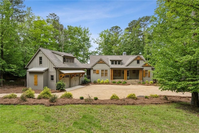 back of house featuring a lawn, dirt driveway, board and batten siding, and covered porch