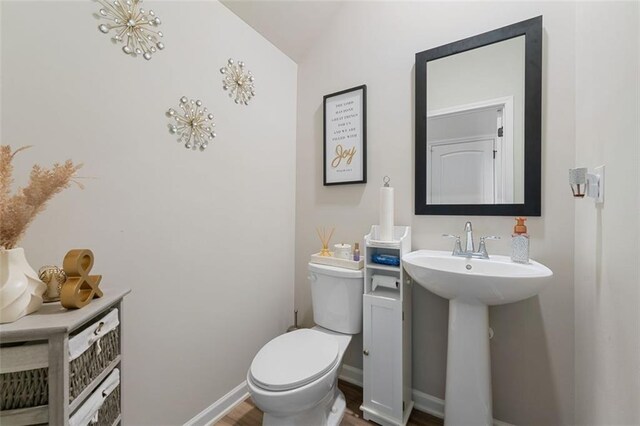 bathroom with sink, toilet, hardwood / wood-style flooring, and vaulted ceiling