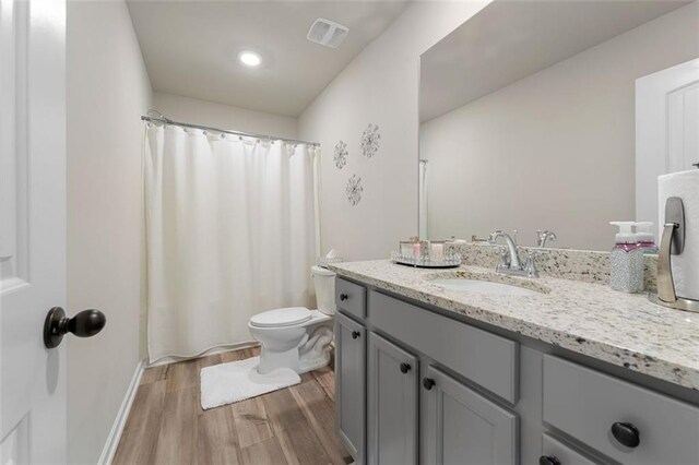 bathroom featuring vanity, a shower with shower curtain, hardwood / wood-style flooring, and toilet