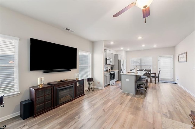 living room with light wood-type flooring and ceiling fan