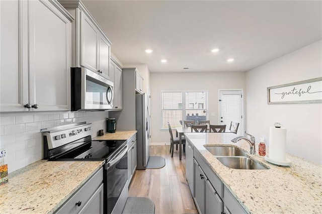 kitchen featuring gray cabinetry, sink, backsplash, stainless steel appliances, and light hardwood / wood-style flooring