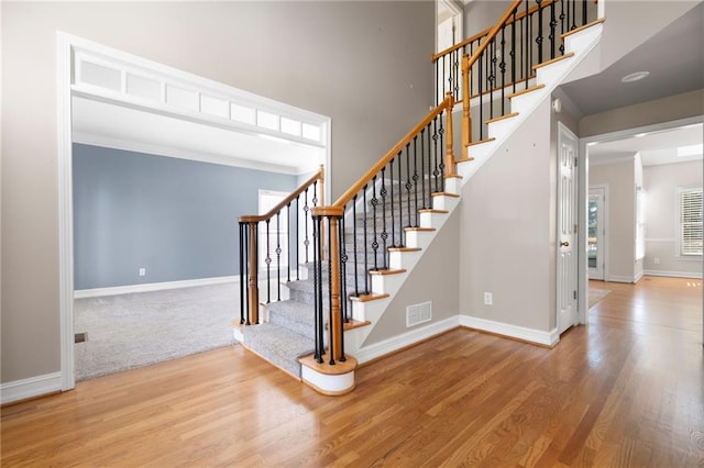 stairway with crown molding and hardwood / wood-style flooring