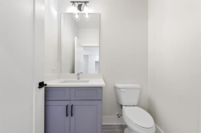 bathroom with vanity, toilet, and hardwood / wood-style flooring