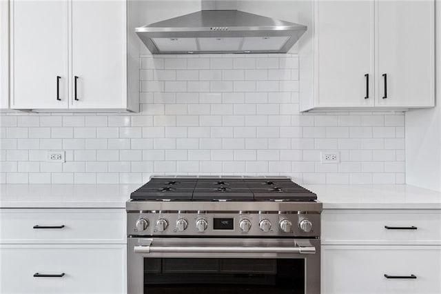 kitchen with wall chimney exhaust hood, high end range, backsplash, and white cabinets