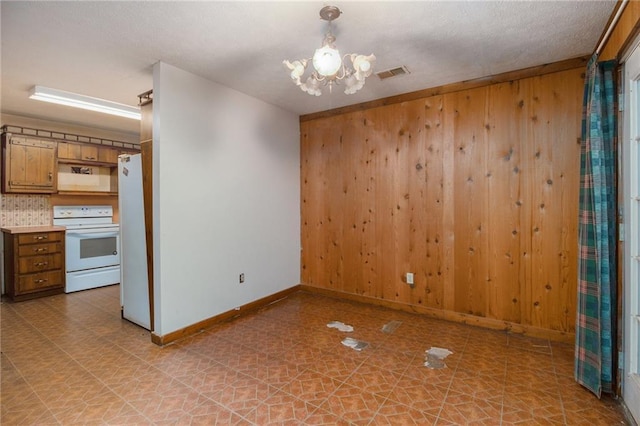 spare room featuring a chandelier and wood walls