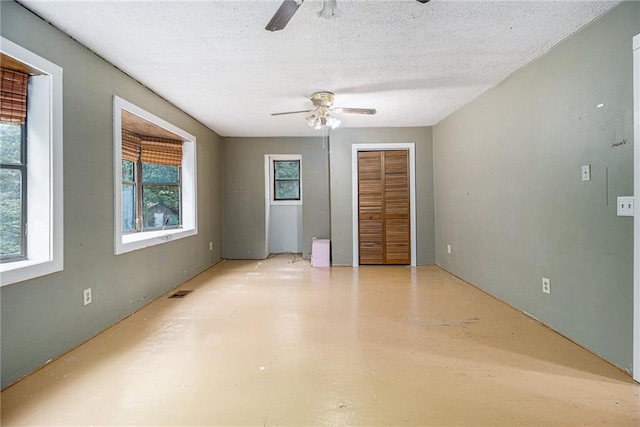 unfurnished bedroom with ceiling fan and a textured ceiling