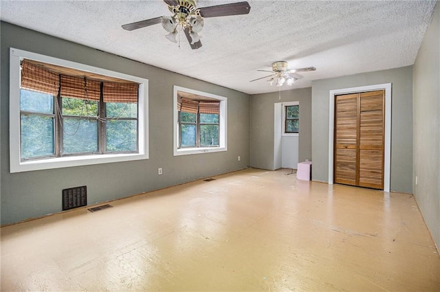 unfurnished bedroom featuring multiple closets, ceiling fan, and a textured ceiling