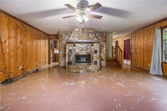 unfurnished living room featuring ceiling fan, a fireplace, a textured ceiling, and wood walls