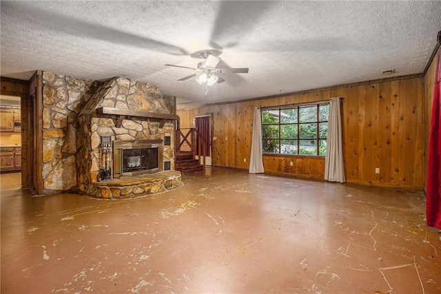 unfurnished living room featuring concrete flooring, wooden walls, a fireplace, ceiling fan, and a textured ceiling