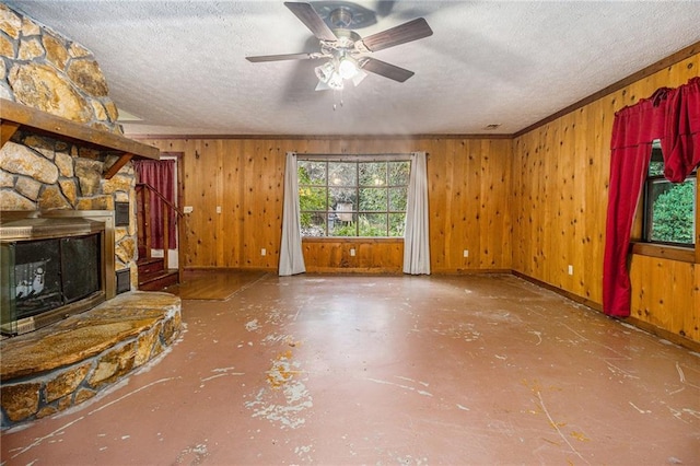 unfurnished living room featuring wooden walls, a wealth of natural light, a fireplace, and a textured ceiling