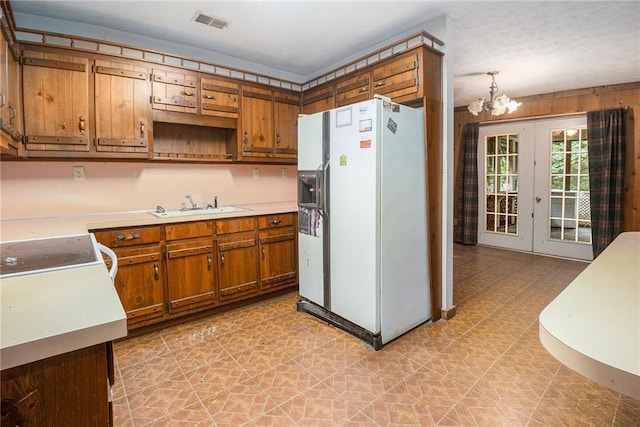 kitchen with sink, white appliances, a notable chandelier, decorative light fixtures, and french doors