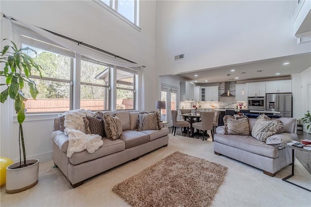 living area with visible vents, recessed lighting, and a high ceiling