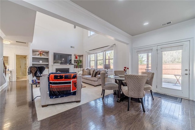 living area with wood finished floors, visible vents, and ornamental molding