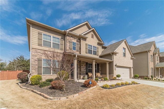 craftsman-style house featuring fence, covered porch, a garage, stone siding, and driveway