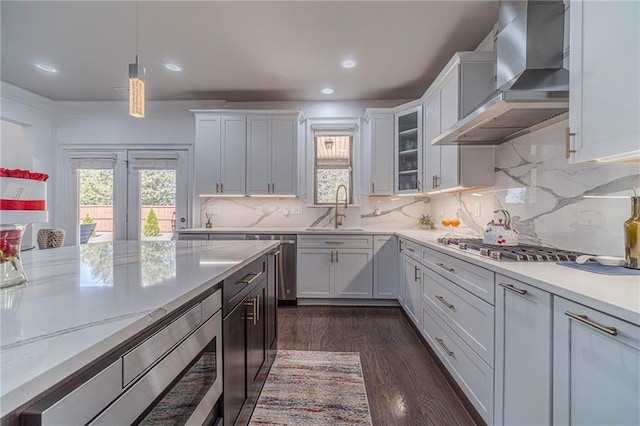 kitchen featuring dark wood-style floors, a sink, appliances with stainless steel finishes, white cabinetry, and wall chimney exhaust hood