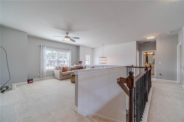 living area with visible vents, light colored carpet, baseboards, and ceiling fan