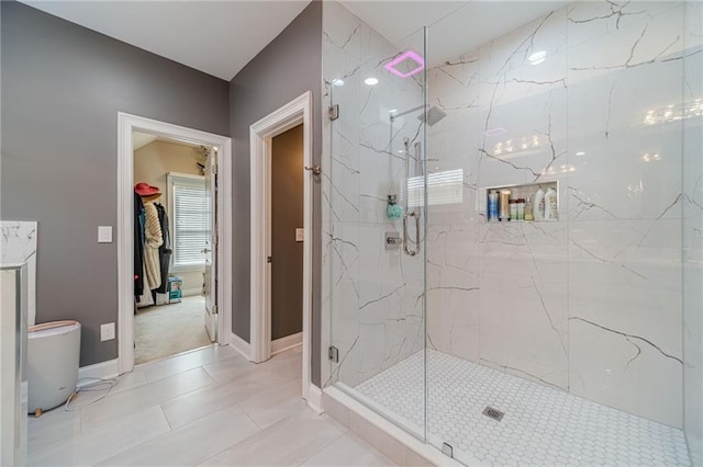 bathroom with a marble finish shower and baseboards