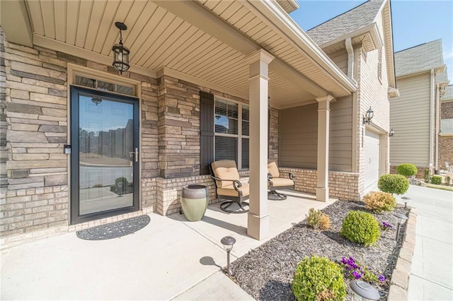 entrance to property with a garage, brick siding, a porch, and concrete driveway