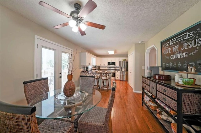 dining space featuring a textured ceiling, light hardwood / wood-style flooring, ceiling fan, and french doors