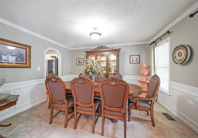 carpeted dining area with a textured ceiling and ornamental molding