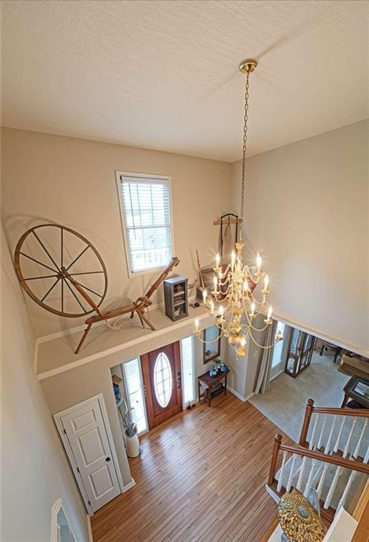 entryway featuring a textured ceiling, hardwood / wood-style floors, and an inviting chandelier