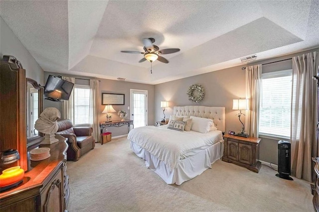 bedroom featuring ceiling fan, a raised ceiling, and light carpet