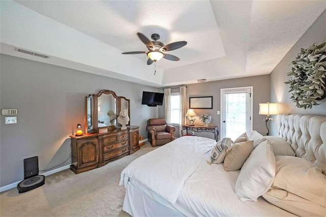 carpeted bedroom with ceiling fan and a raised ceiling